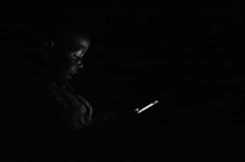 "L'era digitale", foto vincitrice del Primo Premio di Africa 2015 e della categoria Tecnologia, "L'era digitale". Il figlio dell'autore usa il telefonino durante un blackout. Fotografo: Mohsen Taha, 28 anni, Uganda
