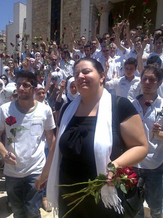 Marcell Shehwaro al funerale di sua madre, assassinata dalle forze del regime siriano a un checkpoint nel giugno 2012. I compagni attivisti rendono tributo portando delle rose rosse. Immagine concessa da Marcell Shehwaro.