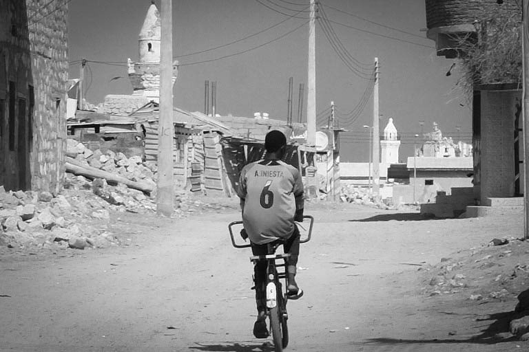 Un ragazzo in bicicletta percorre le strade di Suakin, secoli fa uno dei più importanti centri commerciali del mar Rosso, ora una città abbandonata e semi distrutta. Foto di Angelo Calianno.