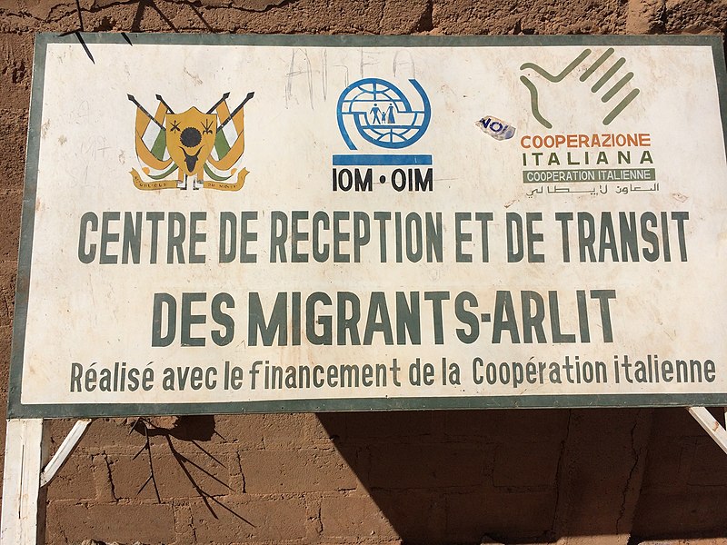 Tabellone all'ingresso della sede IOM a Arlit, Niger settentrionale. Immagine di NigerTZai da Wikimedia Commons